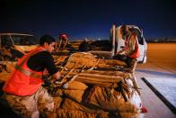 Iraqi soldiers and Iraqi Red Crescent society workers unload trucks with aid that will be shipped on a plane of emergency relief to Syria, in Baghdad