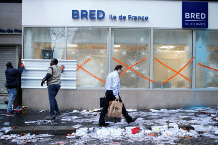 Workmen place a metal panel on the window of a vandalized bank the morning after clashes with protesters wearing yellow vests, a symbol of a French drivers' protest against higher diesel fuel taxes, in Paris, France, December 2, 2018. REUTERS/Stephane Mahe