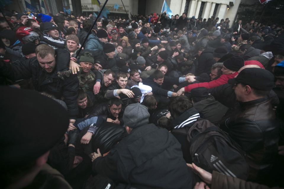 Ukrainian men help pull one another out of a stampede during clashes at rallies held by ethnic Russians and Crimean Tatars in Simferopol