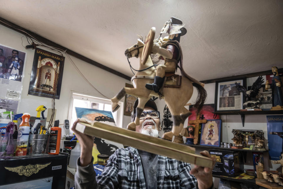 Santero Jerry Sandoval holds one of his bultos depicting St. James, in his studio in Cordova, New Mexico, Friday, April 14, 2023. Sandoval says a prayer to each saint before starting to sculpt their image out of pine, cottonwood or aspen. (AP Photo/Roberto E. Rosales)