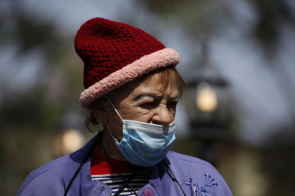 Holocaust survivor Manya Herman wears a mask stands in the street as she keeps a distance from others while attending an annual Holocaust memorial ceremony held outside this year because of the coronavirus in the northern Israeli city of Haifa, Israel, Tuesday, April 21, 2020. (AP Photo/Ariel Schalit)