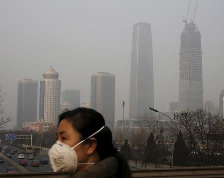 A woman wearing a protective mask makes her way in a business district on a heavily polluted day in Beijing, China January 3, 2016. REUTERS/Kim Kyung-Hoon