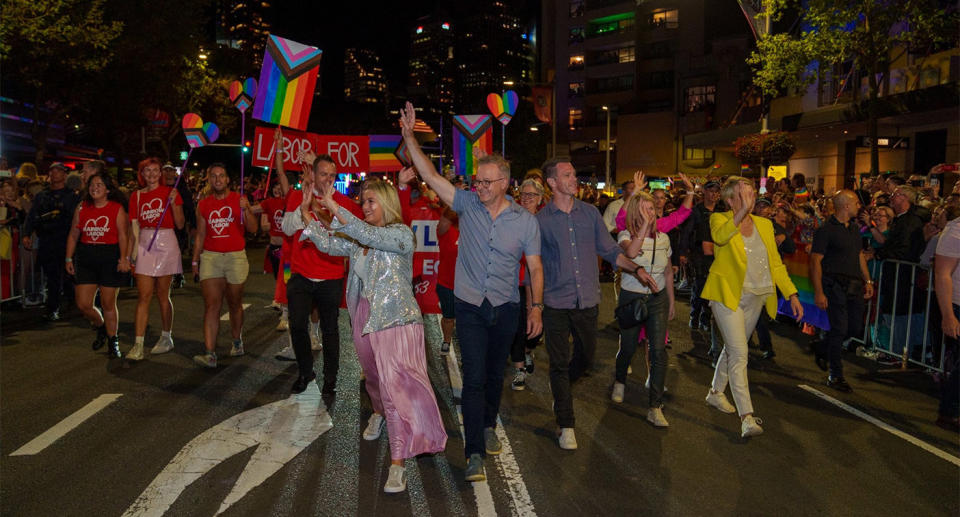 Anthony Albanese waves to the crowd as he marches in the parade