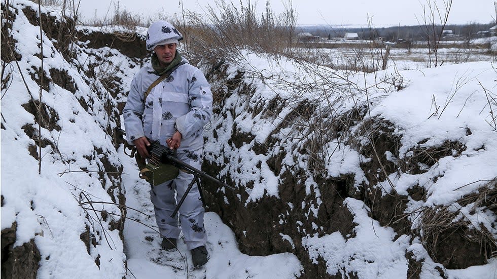 A serviceman holds his machine gun in a trench near eastern Ukraine. 