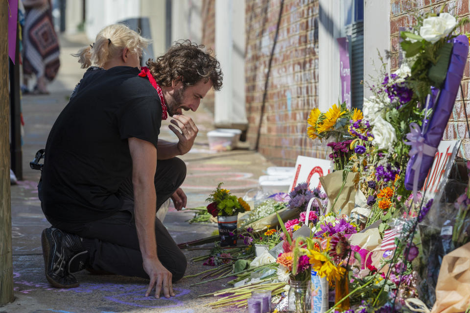 Charlie Spearman, foreground, and Jae Em Cafico kneel at a memorial dedicated to Heather Heyer who was killed during last year's Unite the Right rally, in Charlottesville, Va., Saturday, Aug. 11, 2018. The city of Charlottesville plans to mark Sunday's anniversary of a deadly gathering of white supremacists with a rally against racial hatred. (Craig Hudson/Charleston Gazette-Mail via AP)