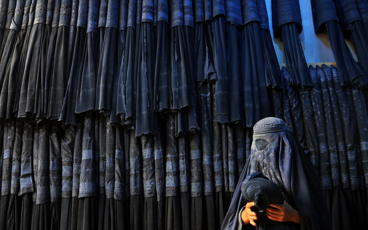 An Afghan woman buying a burka - EPA/SAYED MUSTAFA