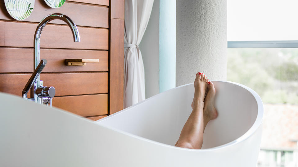 Bare feet in a luxury bathtub on a balcony.