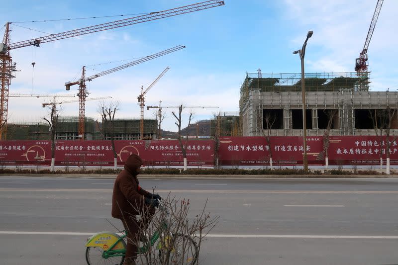 FILE PHOTO: Man rides a bicycle past a Yango Group real estate project under construction in Yanan New Zone