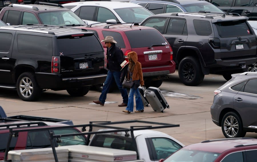 Travelers wade through a parking lot filled with vehicles