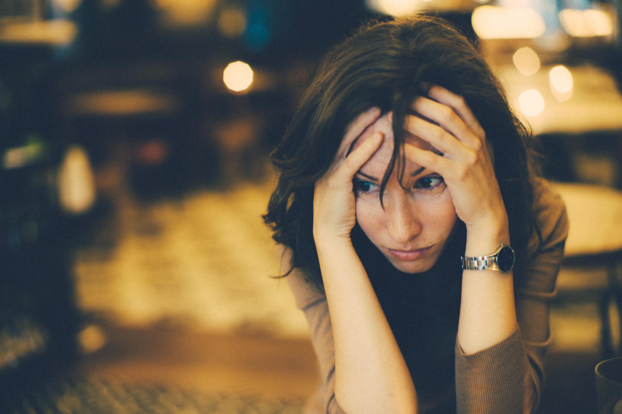 Woman holding head in hands