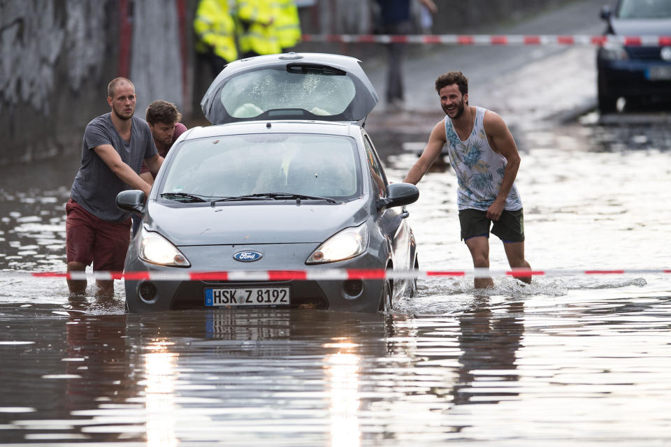 <p>Nach heftigen Regenfällen in Teilen von Nordrhein-Westfalen schieben Männer ein Auto durch die überfluteten Straßen von Köln. (Bild: Marius Becker/dpa) </p>