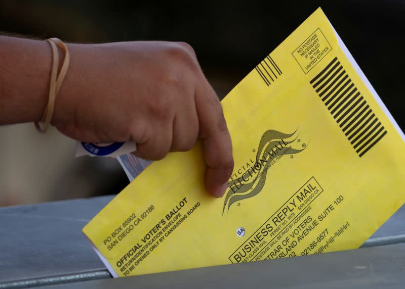 FILE PHOTO: An election worker places mail-in ballots into a voting box at a drive-through drop off location at the Registrar of Voters for San Diego County in San Diego, California