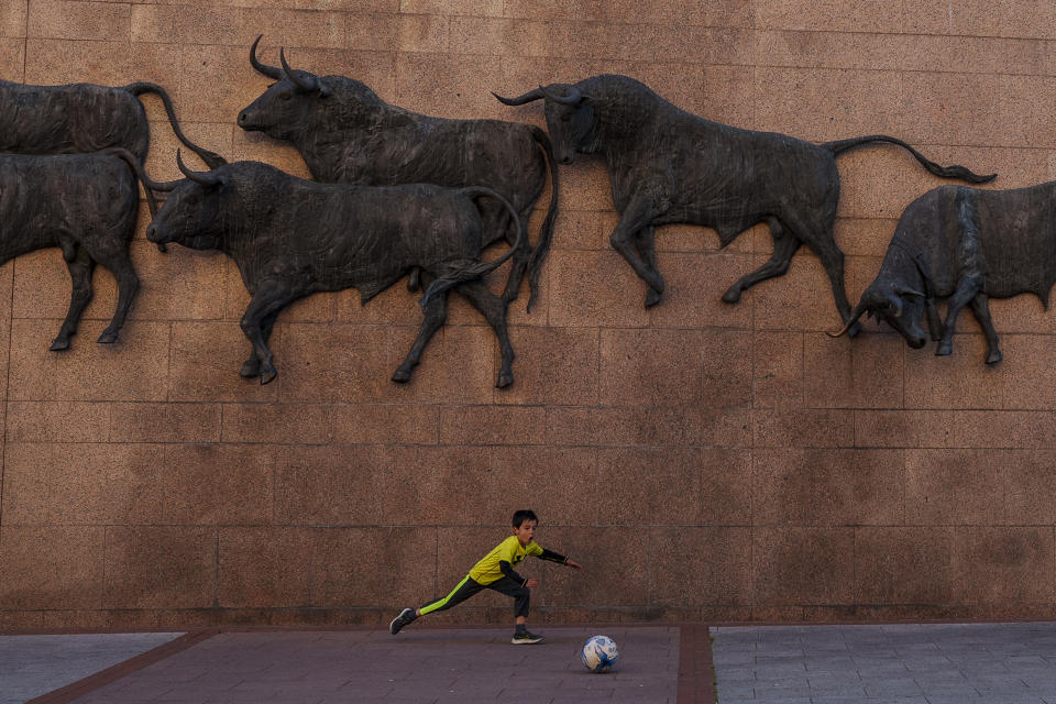 A child plays with a ball in front of a bullfighting monument outside of Las Ventas bullring, in Madrid, Spain, Sunday, March 26, 2023. The death of Spanish bullfighting has been declared many times, but the number of bullfights in the country is at its highest level in seven years, and the young are the most consistent presence as older groups of spectators drop away. (AP Photo/Manu Fernandez)