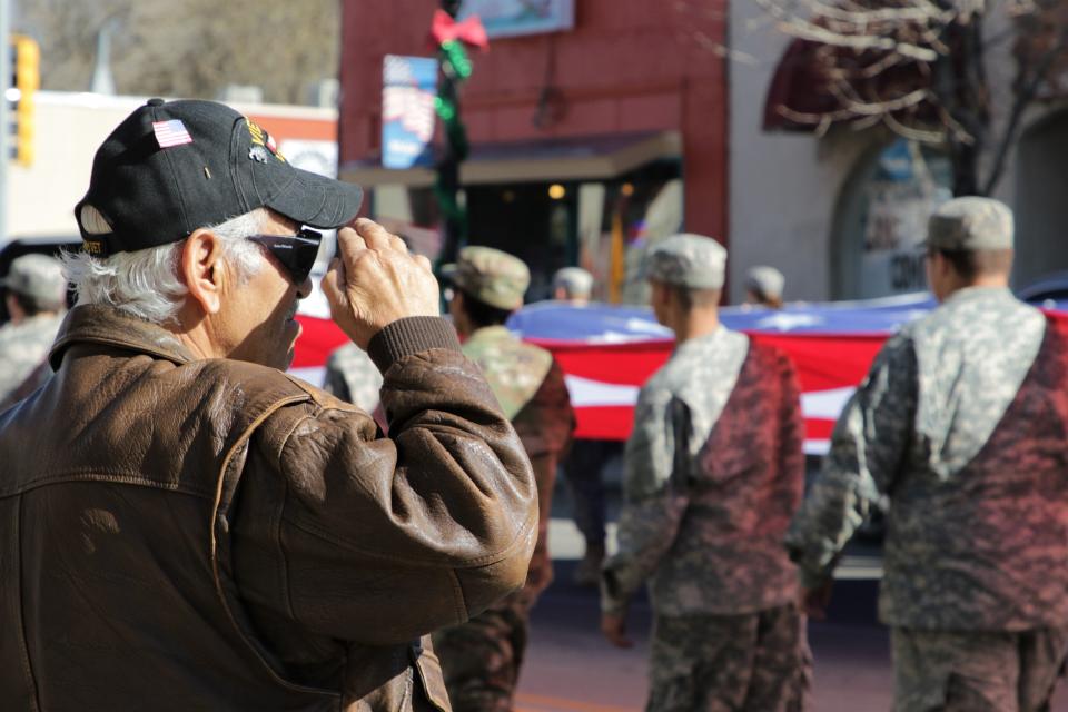 A man salutes a flag carried by passing JROTC students from Aztec High School during the Veterans Day Parade on Nov. 11, 2019 in Aztec.