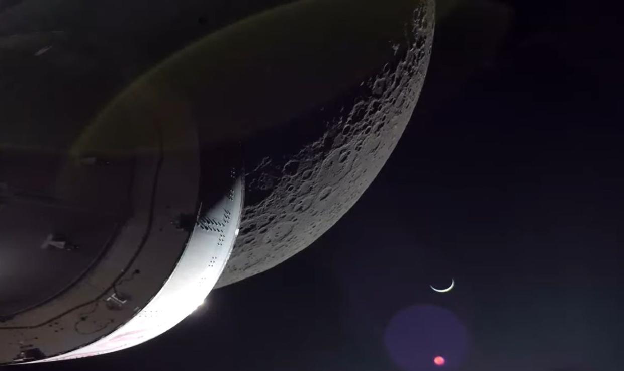 In this screenshot from live coverage of NASA's Orion spacecraft return powered flyby around the moon Earth appears as a crescent toward the bottom of the frame. Orion is on its way back to Earth after Monday's maneuver positioned it for its return trip. A splashdown landing wrapping up the Artemis I mission is expected on Sunday, Dec. 11, in the Pacific Ocean off the coast of California.