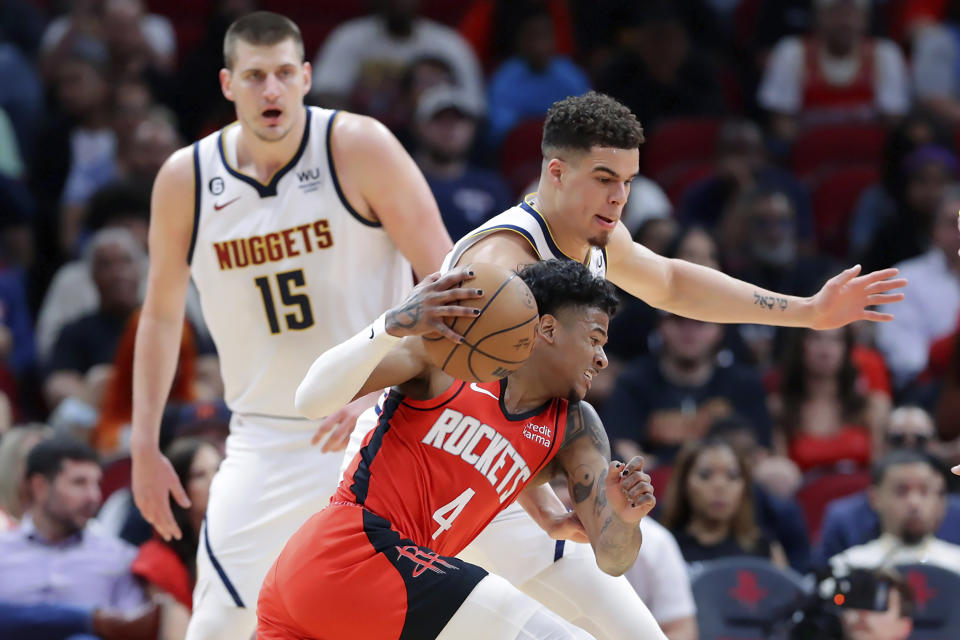 Houston Rockets guard Jalen Green (4) attempts to drive around Denver Nuggets forward Michael Porter Jr., center top, as center Nikola Jokic (15) looks on during the first half of an NBA basketball game, Tuesday, April 4, 2023, in Houston. (AP Photo/Michael Wyke)