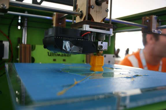 The Ultimaker churns out a tiny, yellow robot figurine.