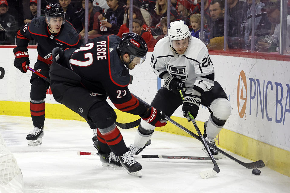Los Angeles Kings' Jaret Anderson-Dolan (28) controls the puck with Carolina Hurricanes' Brett Pesce (22) reaching in during the first period of an NHL hockey game in Raleigh, N.C., Monday, Jan. 15, 2024. (AP Photo/Karl B DeBlaker)