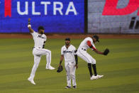 Miami Marlins' Starling Marte, center, watches as Monte Harrison, left, and Lewis Brinson leap to celebrate after they defeated the Philadelphia Phillies in the first game of a baseball doubleheader, Sunday, Sept. 13, 2020, in Miami. (AP Photo/Wilfredo Lee)