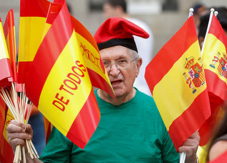 A man wearing a typical Catalan hat hands out Spanish flags during a demonstration in favor of a unified Spain a day before the banned October 1 independence referendum, in Barcelona, Spain, September 30, 2017. REUTERS/Yves Herman