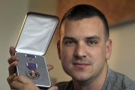 In this Monday, Aug. 20, 2012 photo, Marine Sgt. Ron Strang holds his Purple Heart medal in the living room of his home in Jefferson Hills, Pa., just south of Pittsburgh. In 2008, the federal government created AFIRM, the Armed Forces Institute of Regenerative Medicine, a network of top hospitals and universities around the country, and gave $300 million in grants to spur new treatments using cell science and advanced plastic surgery. Strang is among those benefiting. The 28-year-old former Marine sergeant from Pittsburgh lost half of a thigh muscle to shrapnel, leaving too little to stabilize his gait. "My knee would buckle and I'd fall over," he said. Now, after an experimental cell treatment at the University of Pittsburgh Medical Center, "I'm able to run a little bit" and play a light football game with friends, he said. "It's been a huge improvement." (AP Photo/Keith Srakocic)