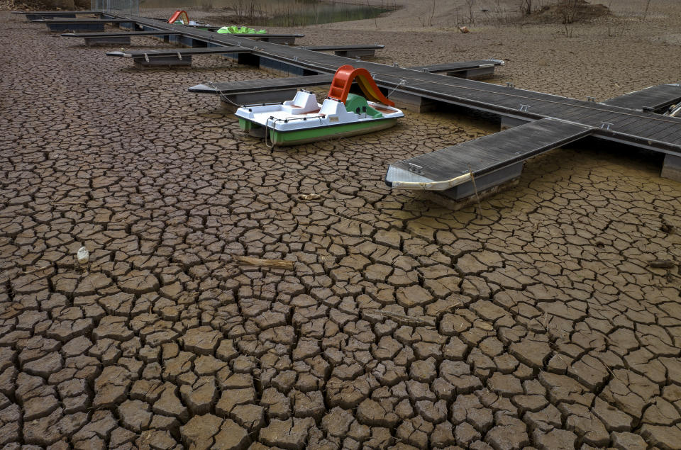 A pedal boat is tied to a dock in a dried part of the Sau reservoir, about 100 km (62 miles) north of Barcelona, Spain, Tuesday, April 18, 2023. Spain's prime minister warned fellow lawmakers Wednesday that the acute drought afflicting the country will become one of its leading long-term concerns. (AP Photo/Emilio Morenatti)