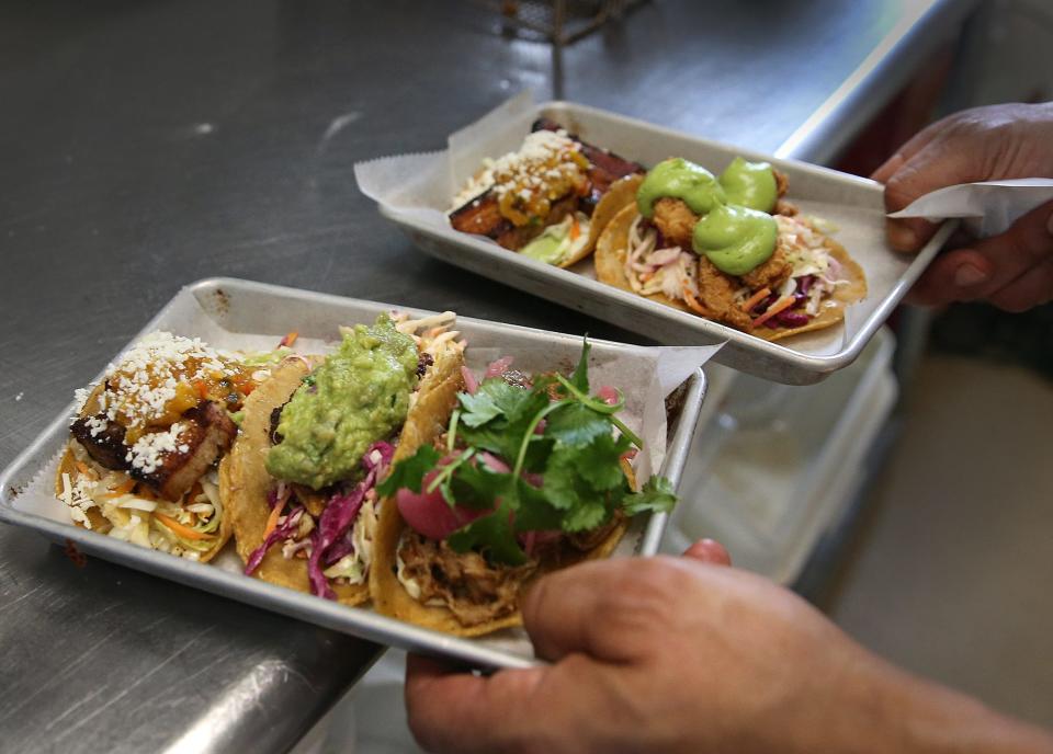 Chef Dave Vargas fills an order of various tacos for a lunch crowd including shrimp, pork belly and carnitas with various salsas and toppings.