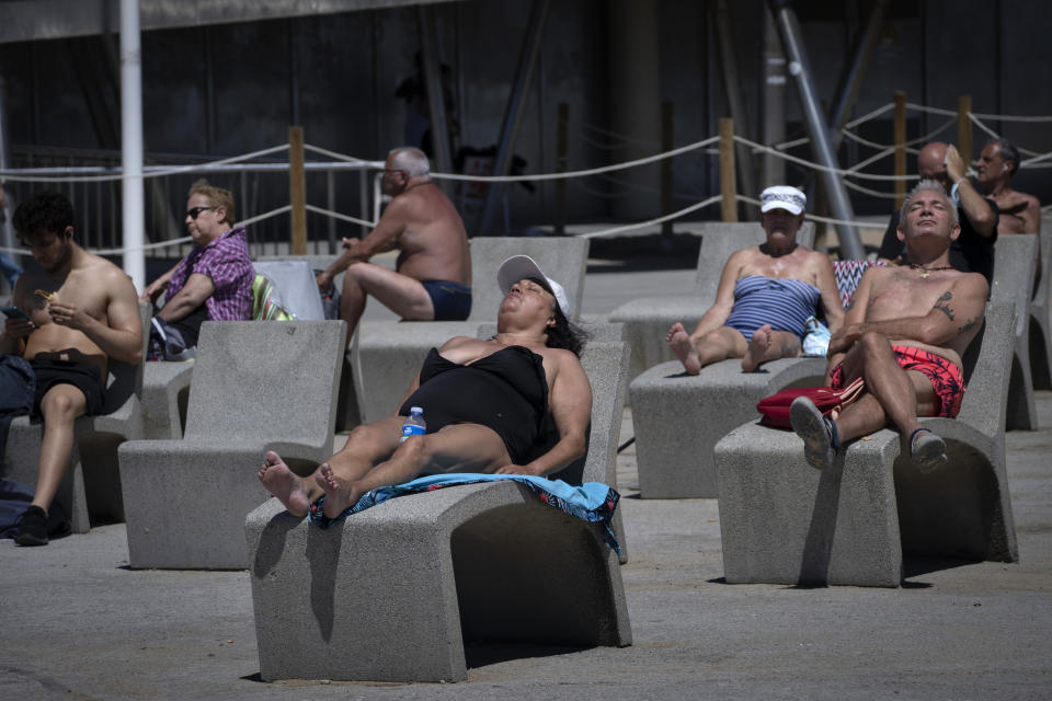 FILE - In this Tuesday, June 8, 2021 file photo, people sunbathe near the beach in Barcelona, Spain. Europe is opening up to Americans and other visitors after more than a year of COVID-induced restrictions. European governments hope to lure back tourists - and their dollars - back to the continent’s trattorias, vistas and cultural treasures. (AP Photo/Emilio Morenatti, File)