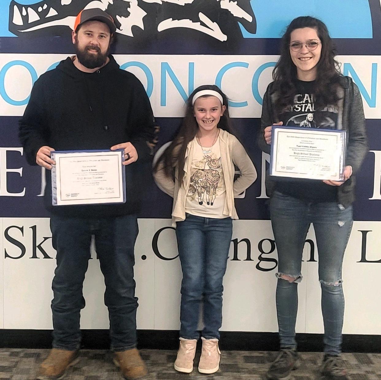 David and Taci Dean with high school diplomas earned from the Coshocton County Career Center's new adult education program in partnership with the Buckeye Career Center. David also got certification in welding and started a job at Crozier Welding and Taci completed a course in business and marketing. With them is their 9-year-old daughter Elaina.