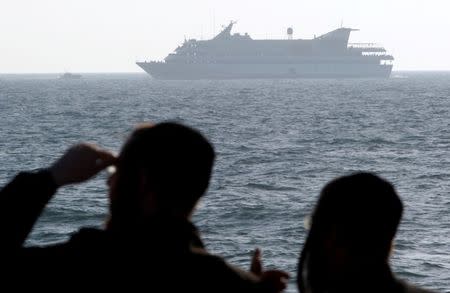 Ultra-orthodox Jews watch as the Mavi Marmara, a Gaza-bound ship that was raided by Israeli marines, is escorted to Ashdod port by an Israeli naval vessel (not seen) May 31, 2010. REUTERS/Amir Cohen/File Photo