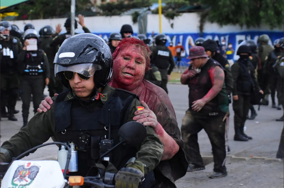 Police rescue Vinto mayor Patricia Arce Guzman on a motorcycle after people threw paint and dirt on her following a fire in Vinto's Town Hall, in Quillacollo, Bolivia, on Nov. 6, 2019. | Daniel James—Los Tiempos Bolivia via Reuters