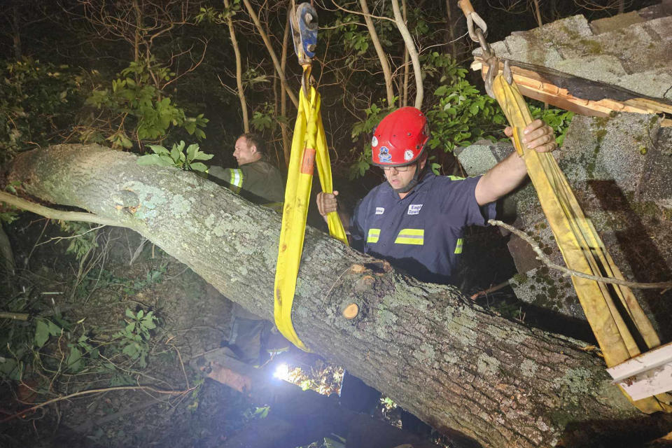Crew from Eagle Towing removes a fallen tree that destroyed a cabin and trapped a counselor for 90 minutes Thursday, June 20, 2024, at Camp Ao-Wa-Kiya in Oceana County, Mich. Police said there were 14 people, including 12 girls, in the cabin. (Andrew Heykoop/Eagle Towing via AP)