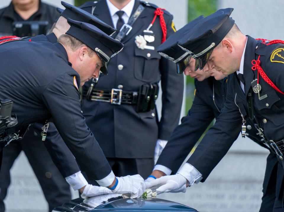 Traditional carnations being placed on the casket as the committal service for Officer Seara Burton is held Monday, Sept. 26, 2022, at Crown Hill Cemetery in Indianapolis. Burton was appointed to the Richmond Police Department on Aug. 6, 2018. She was shot during a traffic stop in August and died from her injuries Sept. 18, 2022.