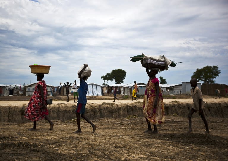 A woman, her cousin, her son and her son's friend carry their belongings as they walk through the United Nations base outside Bentiu, which hosts around 118,000 people uprooted during the country's 21-month old civil war