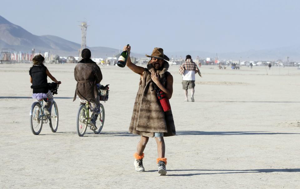 A Burning Man participant toasts the sunrise with a bottle of champagne at the 2013 Burning Man arts and music festival in the Black Rock desert of Nevada, August 30, 2013. The Burning Man organization received approval from the federal government to have a maximum of 68,000 participants attend the festival. REUTERS/Jim Bourg (UNITED STATES - Tags: SOCIETY) FOR USE WITH BURNING MAN RELATED REPORTING ONLY. FOR EDITORIAL USE ONLY. NOT FOR SALE FOR MARKETING OR ADVERTISING CAMPAIGNS. NO THIRD PARTY SALES. NOT FOR USE BY REUTERS THIRD PARTY DISTRIBUTORS