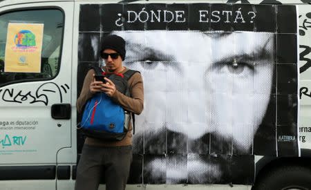 A man looks at his cell phone in front of a portrait of Santiago Maldonado, a protester who has been missing since security forces clashed with indigenous activists in Patagonia on August 1, 2017, at a demonstration to demand actions to find him, in Buenos Aires, Argentina September 1, 2017. Words on the banner read "Where is he?". Picture taken September 1, 2017. REUTERS/Marcos Brindicci