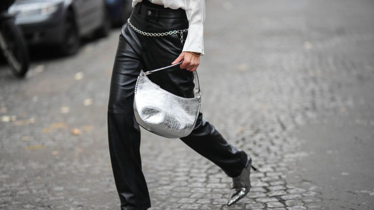 paris, france december 03 natalia verza wears a white silk buttoned shirt, a silver shiny varnished leather shoulder bag, black shiny leather large wide legs pants, a silver chain belt, black with embroidered silver sequined pointed heels ankle shoes , bracelet, during a street style fashion photo session, on december 03, 2022 in paris, france photo by edward berthelotgetty images
