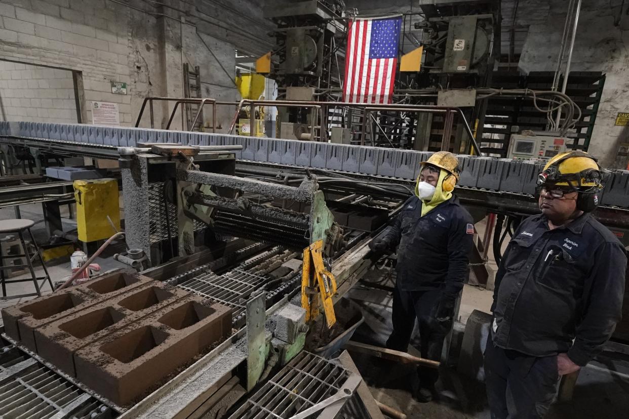 Workers monitor a production line of concrete blocks created with liquid carbon dioxide as an ingredient at the Glenwood Mason Supply Company, Tuesday, April 18, 2023, in the Brooklyn borough of New York. New York is forcing buildings to clean up, and several are experimenting with capturing carbon dioxide, cooling it into a liquid and mixing it into concrete where it turns into a mineral. (AP Photo/John Minchillo)