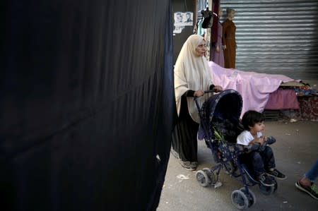 A woman walks next to a black flag during a strike called by local activists against U.S. President Donald Trump's "Deal of the Century" at Al-Baqaa Palestinian refugee camp, near Amman