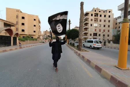 A member loyal to the Islamic State in Iraq and the Levant (ISIL) waves an ISIL flag in Raqqa June 29, 2014. REUTERS/Stringer