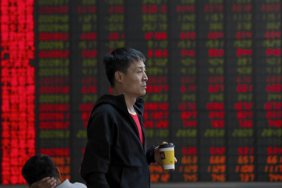 In this Thursday, Sept. 19, 2019, photo, a man holding a cup of coffee monitors the stock prices at a brokerage house in Beijing. Asian shares were mostly higher on Friday, Sept. 20, 2019 after a lackluster session on Wall Street, as investors shifted their focus to China-U.S. trade talks after a busy week of central bank news. (AP Photo/Andy Wong)