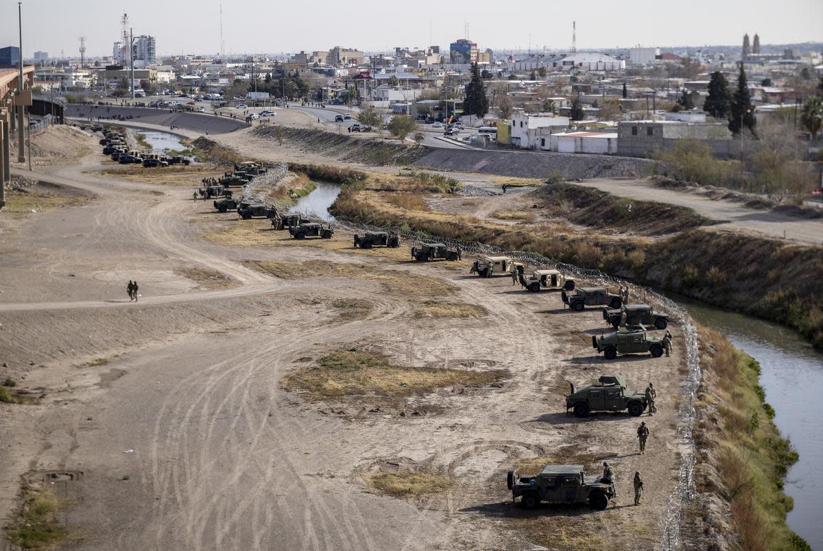 Texas National Guard and Texas DPS officers position themselves on the banks of the Rio Grande, Tuesday, Dec. 20, 2022, in El Paso. Over 400 personnel have been sent to this border sector by Governor Abbott after El Paso city officials declared a state of emergency.