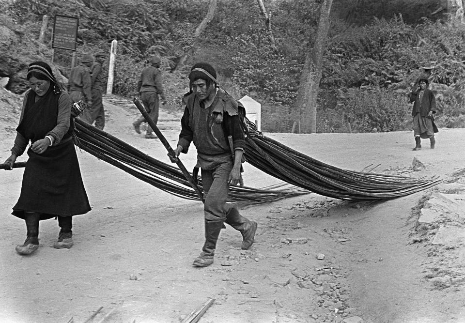 FILE - Two Tibetans haul long sticks of wood along a mountain road in the North East Frontier Area as they aid the Indians in battling the Chinese Red invaders, Nov. 15, 1962. The Tibetans, refugees from the fighting front, had settled in the area after being driven from their home. (AP Photo/Dennis Lee Royle, File)