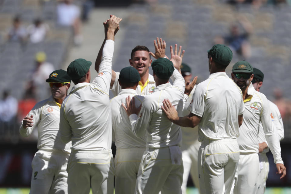 Australia's Josh Hazlewood, center, is swamped by team-mates after taking the wicket of India's Cheteshwar Pujara during play in the second cricket test between Australia and India in Perth, Australia, Monday, Dec. 17, 2018. (AP Photo/Trevor Collens)