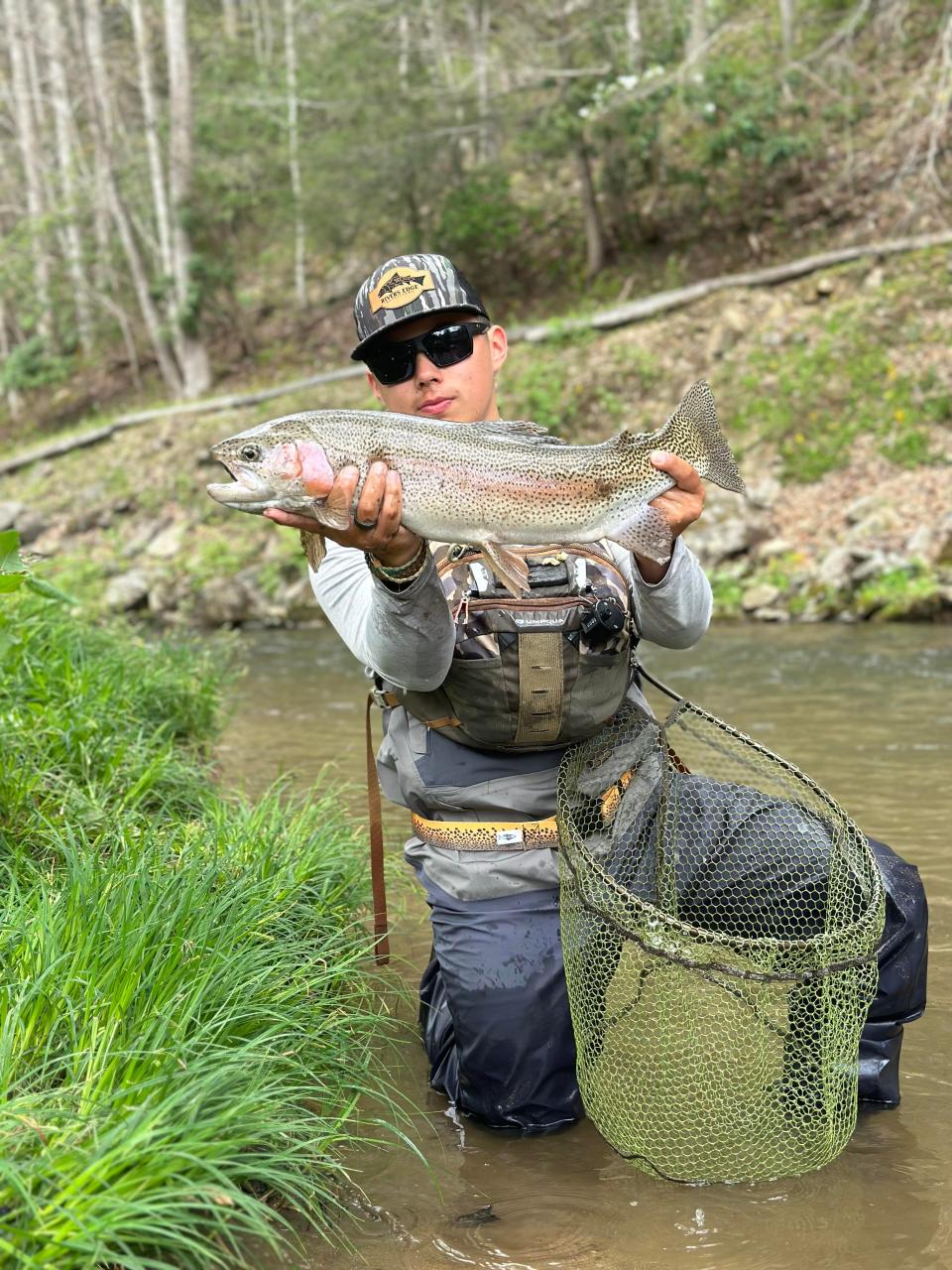 AJ Allison holds a rainbow trout caught in stream in Cherokee, North Carolina.