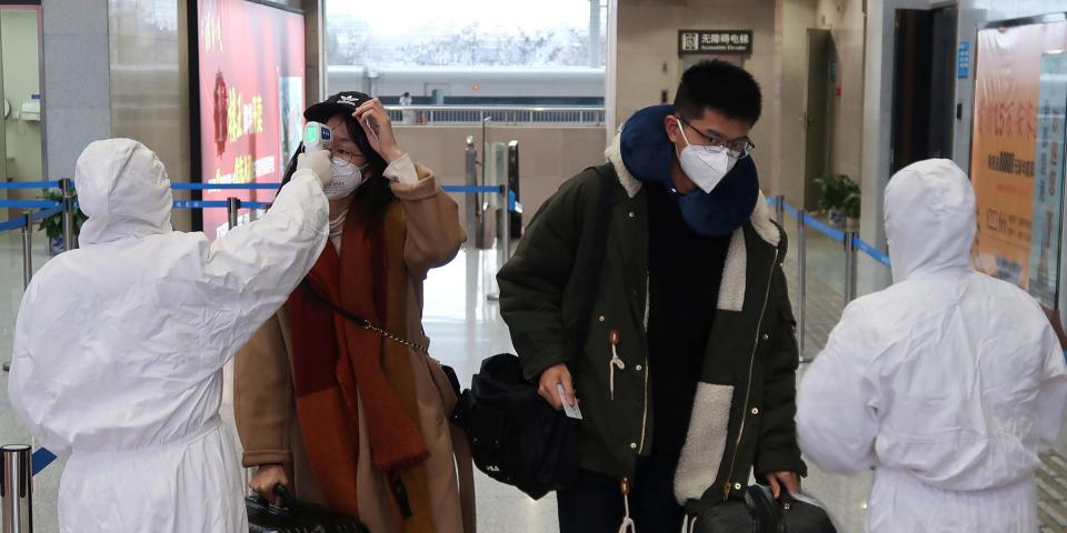 Workers in protective suits check the temperature of passengers arriving at the Xianning North Station on the eve of the Chinese Lunar New Year celebrations, in Xianning, a city bordering Wuhan to the north, in Hubei province, China January 24, 2020. REUTERS/Martin Pollard