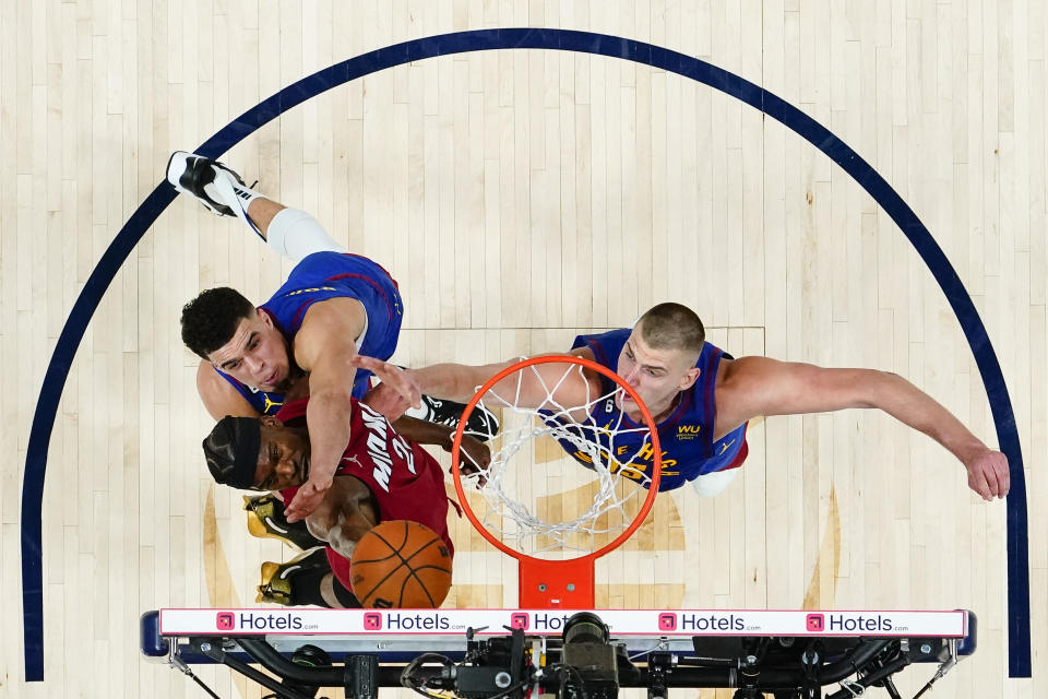 Miami Heat forward Jimmy Butler (22) shoots while defended by Denver Nuggets forward Michael Porter Jr., left, and center Nikola Jokic, right, during the second half of Game 1 of basketball's NBA Finals, Thursday, June 1, 2023, in Denver. (AP Photo/Jack Dempsey, Pool)