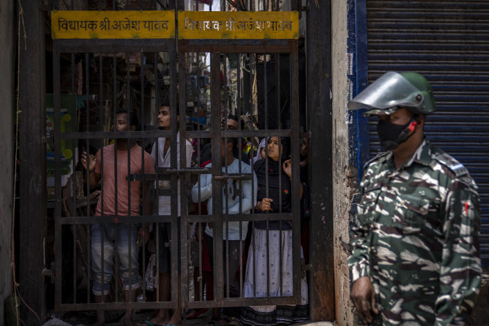 An Indian paramilitary solider stands guard as residents watch from behind a bolted iron gate during the demolition of Muslim-owned shops in New Delhi's northwest Jahangirpuri neighborhood on April 20, 2022.<span class="copyright">Altaf Qadri—AP</span>