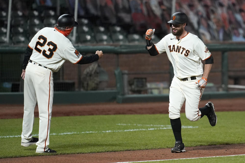 San Francisco Giants' Brandon Belt, right, is congratulated by third base coach Ron Wotus after hitting a two-run home run against the Seattle Mariners during the third inning of a baseball game in San Francisco, Wednesday, Sept. 16, 2020. This is a makeup of a postponed game from Tuesday in Seattle. (AP Photo/Jeff Chiu)