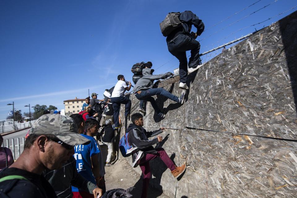 <p>A group of Central American migrants -mostly from Honduras- get over a fence as they try to reach the US-Mexico border near the El Chaparral border crossing in Tijuana, Baja California State, Mexico, on November 25, 2018.</p>
